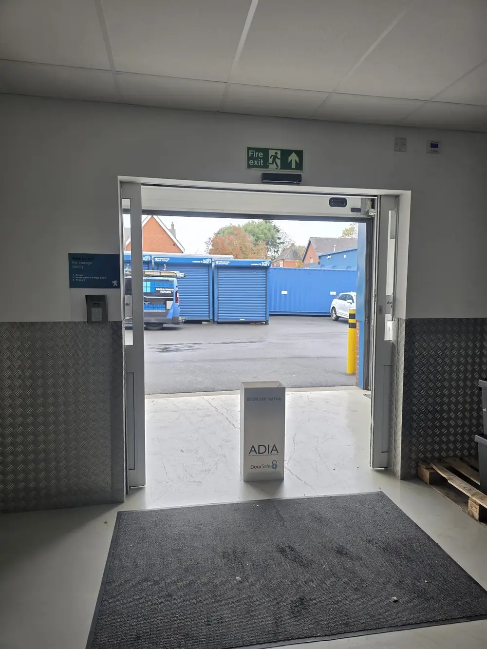 ADIA DoorSafe BS EN 16005 test body at an automatic door during a safety check, company van outside