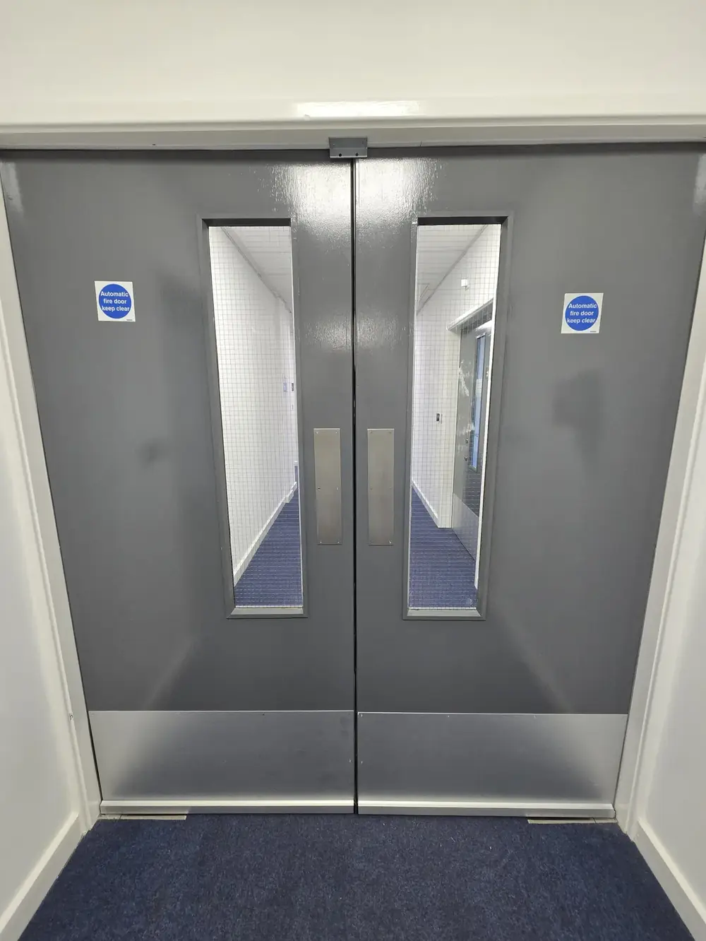 Automatic fire doors with hold-open devices in a corridor