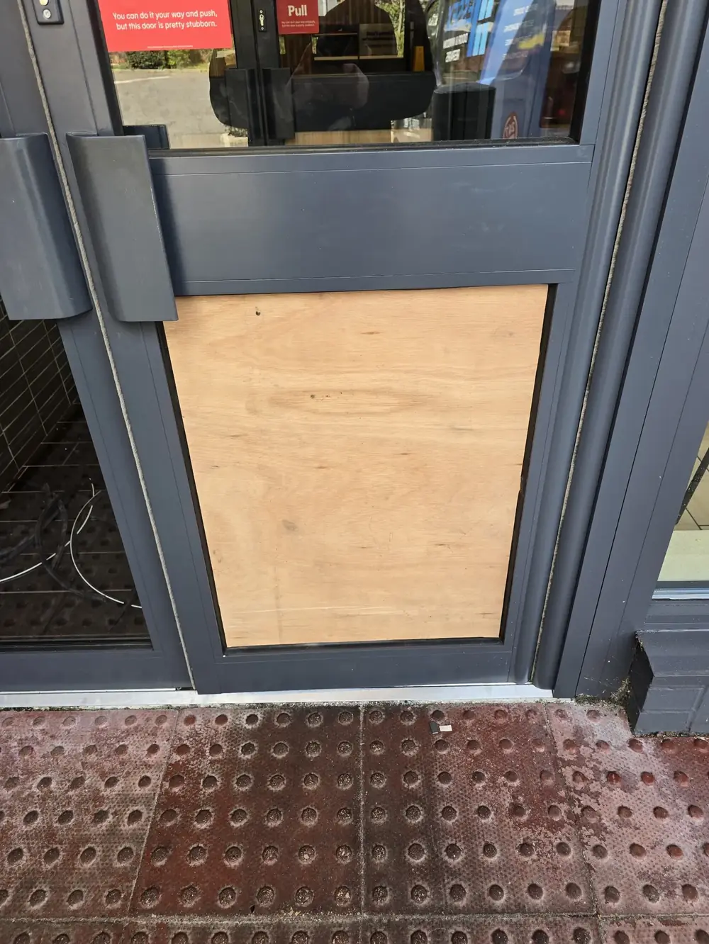 Shopfront door panel boarded to make the entrance secure