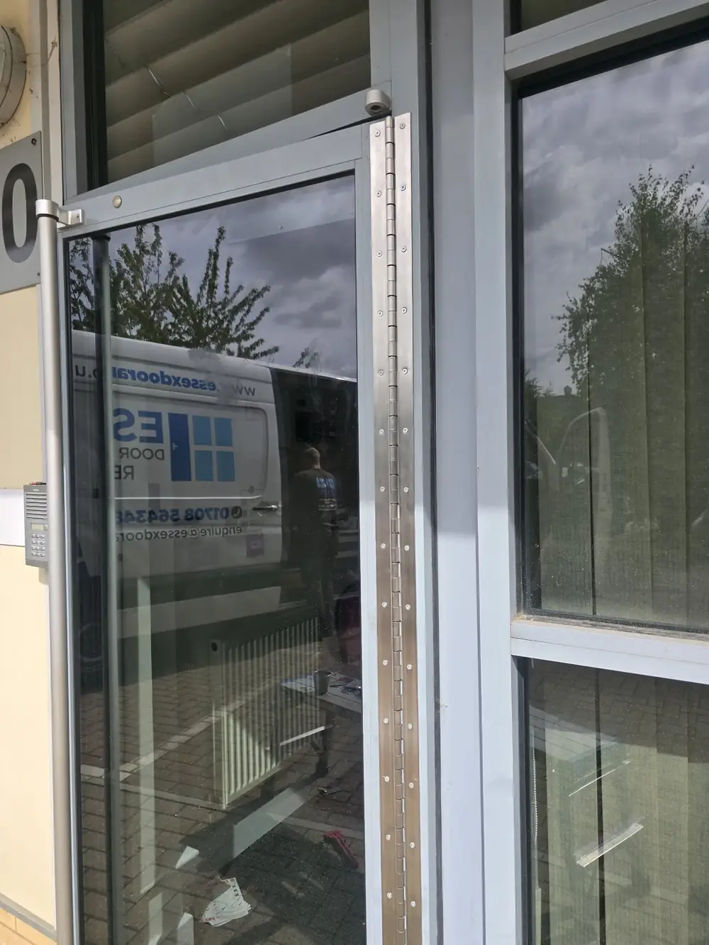Aluminium entrance door fitted with a new continuous hinge, company van reflected in the glass